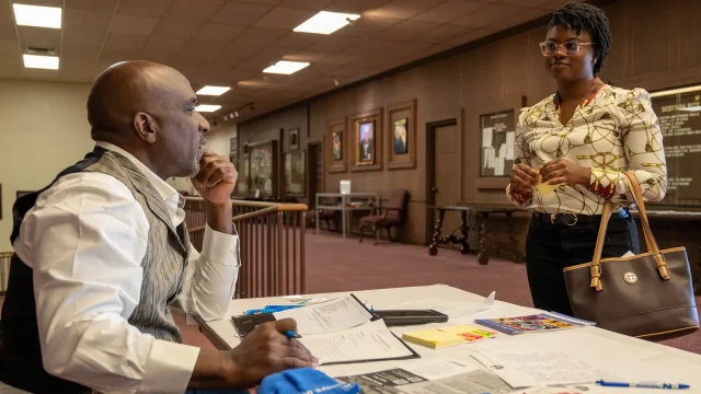An adviser seated at a table talks with a job seeker at a career fair for veterans