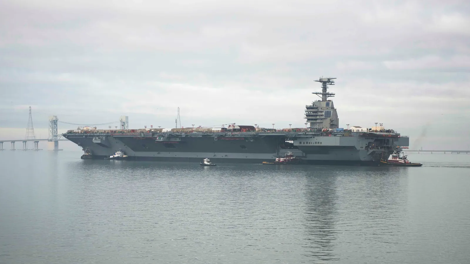 The aircraft carrier Gerald R. Ford is moved along the James River by tugboats after its launch in November 2013