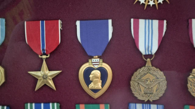 Military medals including a Bronze Star and a Purple Heart mounted in a display case with red backing
