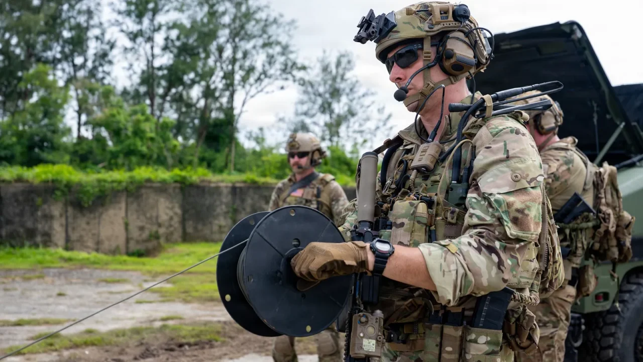 A Navy explosive ordnance disposal technician in combat gear holds a spool of tubing during a training drill on Guam