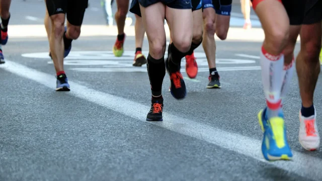 Close view of runners' legs and running shoes on an asphalt road