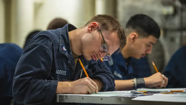 A Navy sailor fills in an answer sheet with a pencil during the E-5 Navy-wide advancement exam aboard an aircraft carrier