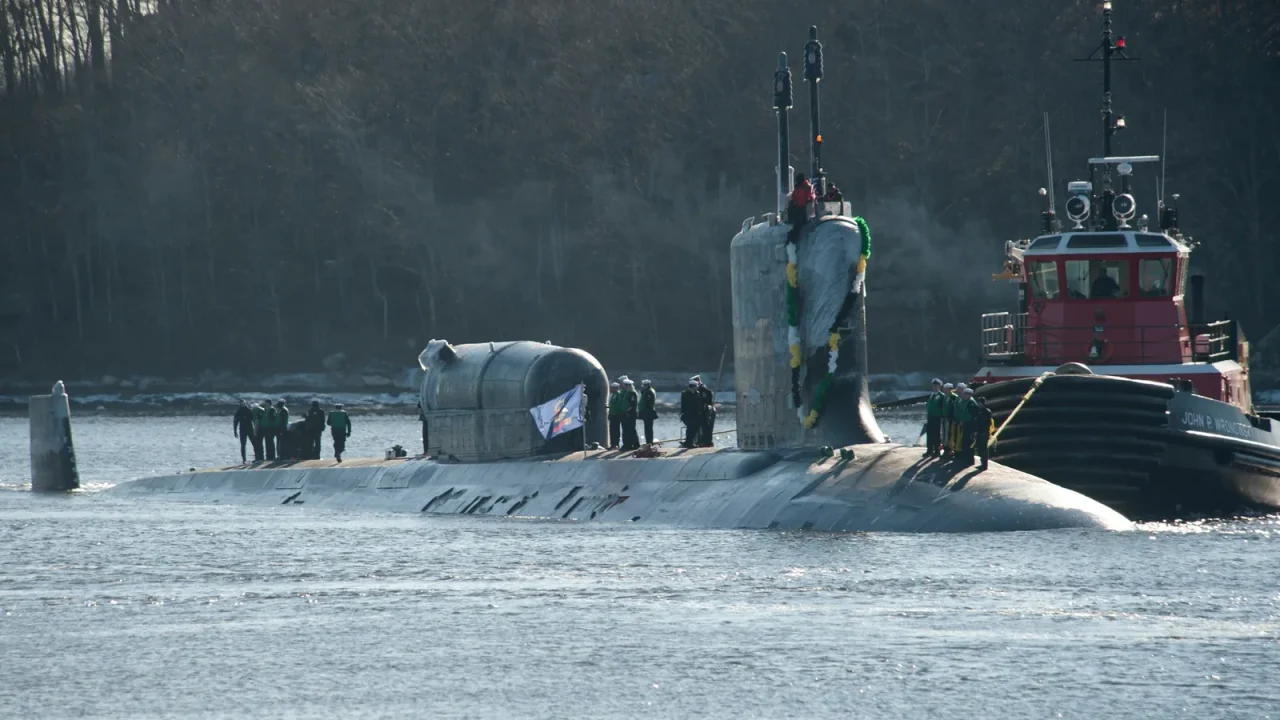 The Virginia-class submarine USS North Dakota on the surface with a tugboat alongside as it returns to Submarine Base New London