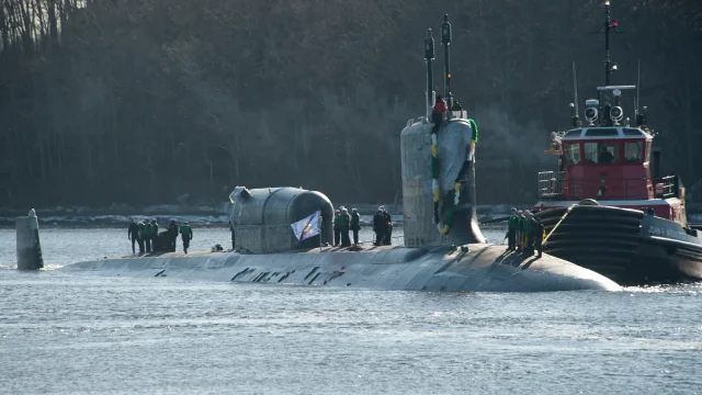 The Virginia-class submarine USS North Dakota on the surface with a tugboat alongside as it returns to Submarine Base New London