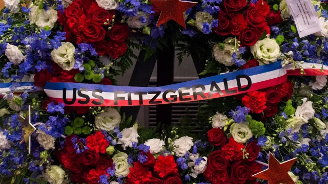 A memorial wreath of red roses, white flowers and blue blooms with a red, white and blue ribbon that reads USS Fitzgerald