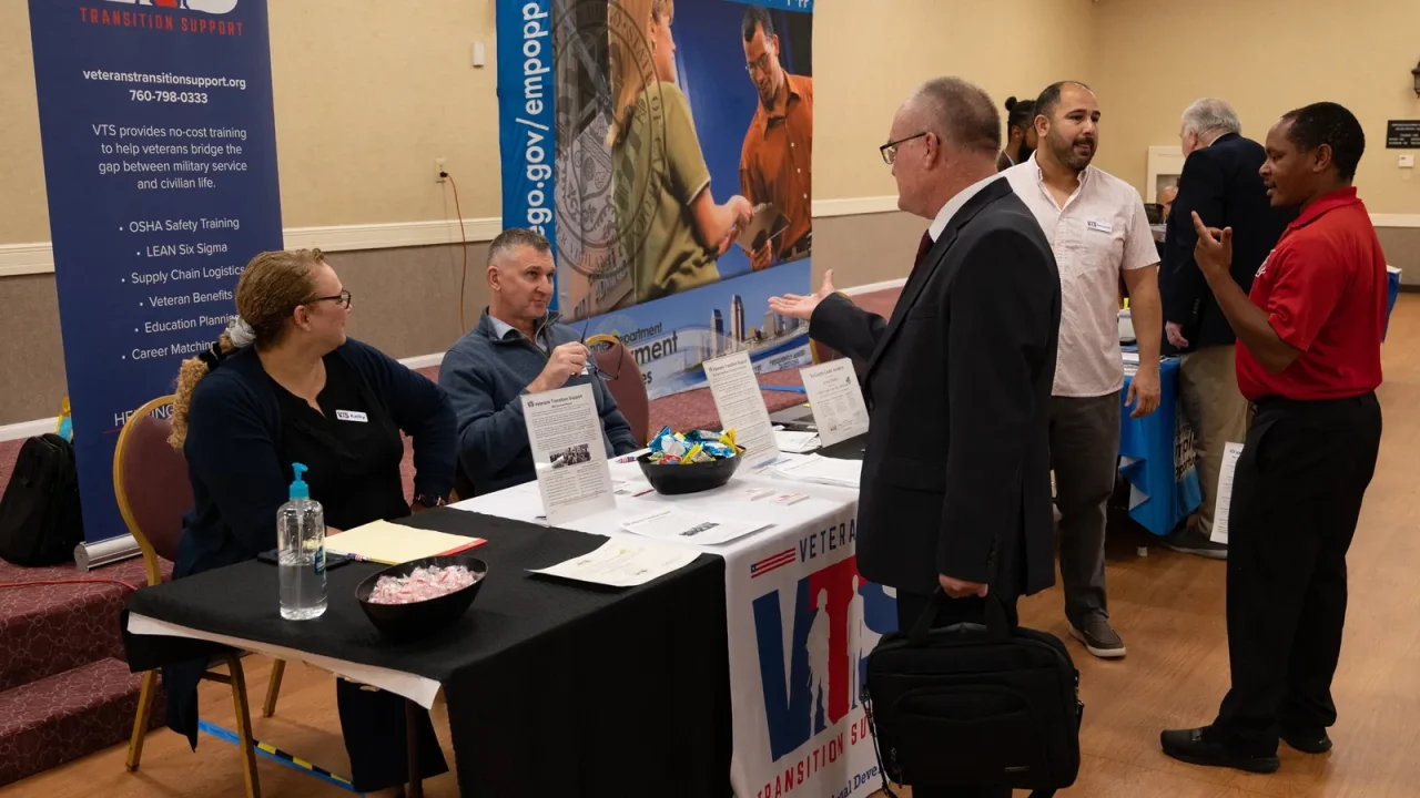 Veterans talk with employers and training providers at tables during a career fair